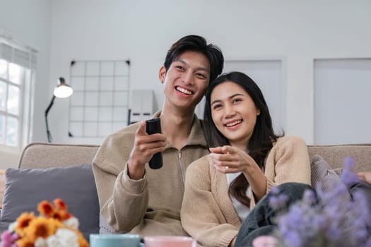 A young couple happily watches a TV program together on the sofa. and enjoy embracing each other with love and romance.