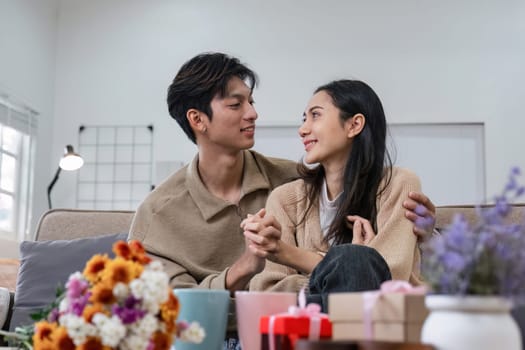 Young couple hugging and showing their love to each other. And give bouquets of flowers to each other on special days or Valentine's Day. On the sofa in the living room.