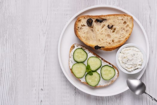Olive bread with cottage cheese and cucumbers, with copy space for text.