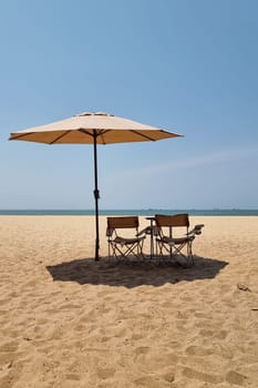 Rayong Thailand 13 March 2024, Two chairs sit nestled under a colorful umbrella on a serene sandy beach, inviting relaxation and enjoying the scenic ocean view.