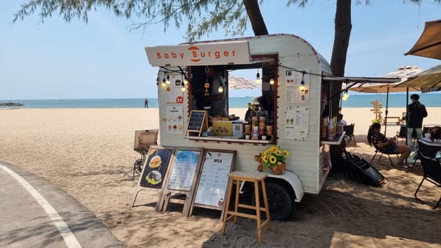 Rayong Thailand 13 March 2024, A vibrant food truck is parked on the sandy beach, serving up delicious meals to beachgoers under the sunny sky.