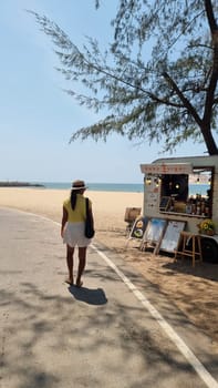 Rayong Thailand 13 March 2024, A stylish man walking down a bustling street lined with food carts, enjoying the sights and smells of street food vendors.