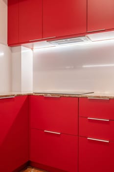 A modern kitchen corner showcasing bold red cabinetry against a white backdrop