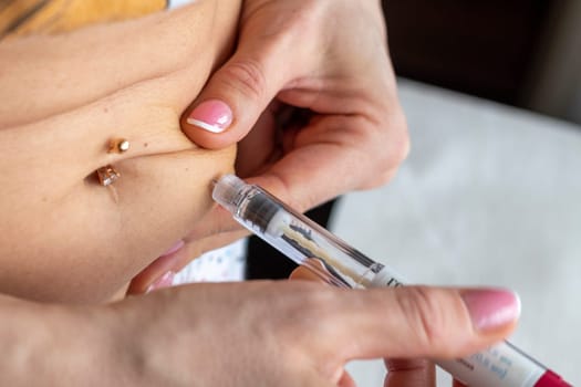 Close up shot of the woman with beautiful hands, preparing hormone medicine and injecting herself to the abdomen with pierced bellybutton.