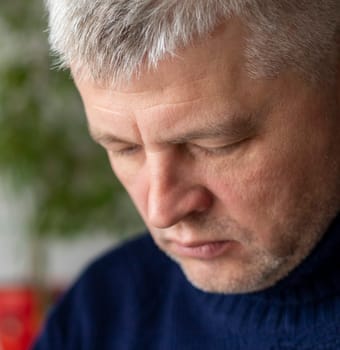 Portrait of the mid aged man with grey hair, wearing warm, dark blue sweater