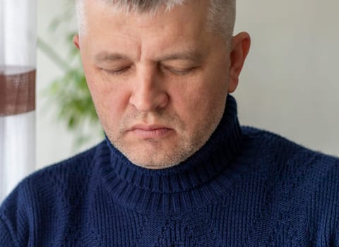 Portrait of the mid aged man with grey hair, wearing warm, dark blue sweater