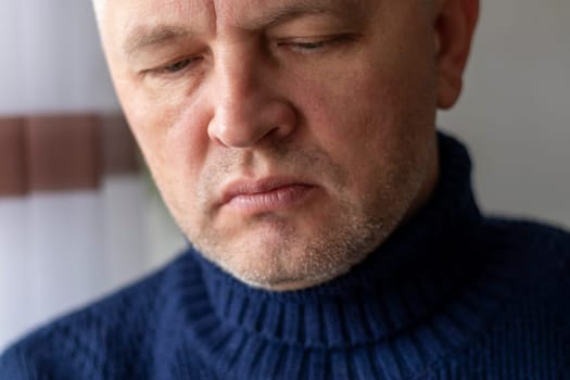 Portrait of the mid aged man with grey hair, wearing warm, dark blue sweater