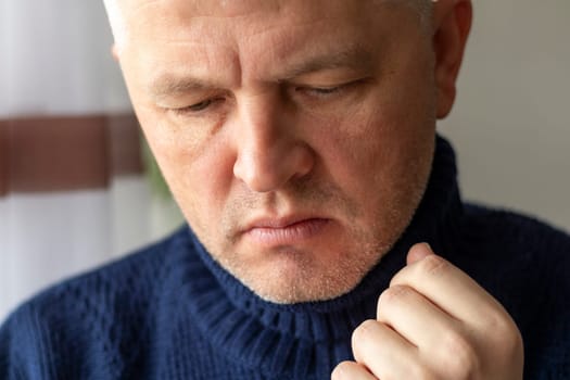 Portrait of the mid aged man with grey hair, wearing warm, dark blue sweater