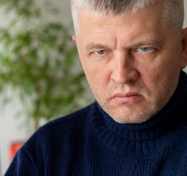 Portrait of the mid aged man with grey hair, wearing warm, dark blue sweater