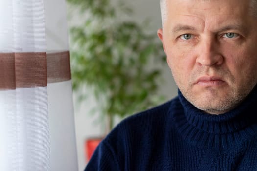 Portrait of the mid aged man with grey hair, wearing warm, dark blue sweater