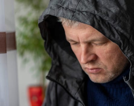 Portrait of the mid aged man with grey hair, wearing warm, dark blue sweater and grey coat.