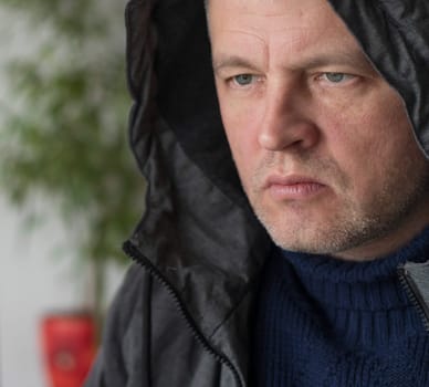 Portrait of the mid aged man with grey hair, wearing warm, dark blue sweater and grey coat.