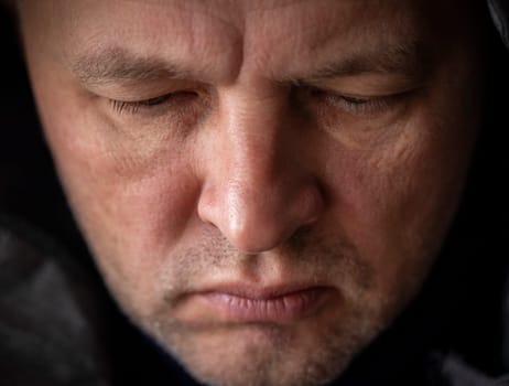 Portrait of the mid aged man with grey hair, wearing warm, dark blue sweater and grey coat.