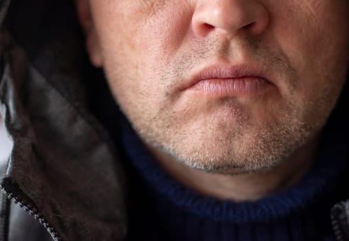 Portrait of the mid aged man with grey hair, wearing warm, dark blue sweater and grey coat.