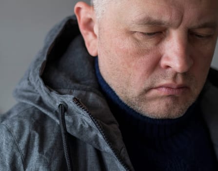 Portrait of the mid aged man with grey hair, wearing warm, dark blue sweater and grey coat.