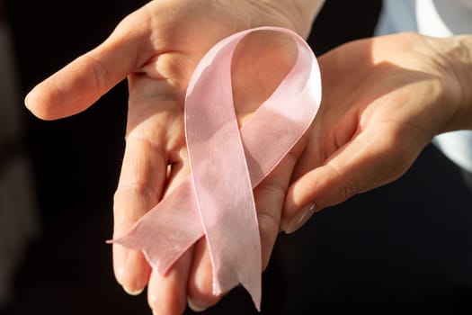 Shot of a woman holding pink ribbon, symbol of a breast cancer awareness.