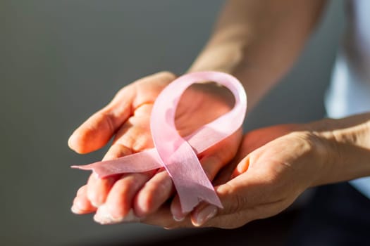 Shot of a woman holding pink ribbon, symbol of a breast cancer awareness.