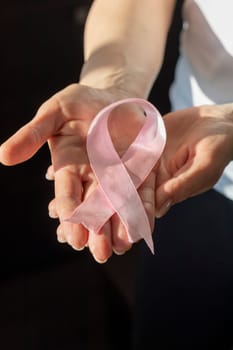 Shot of a woman holding pink ribbon, symbol of a breast cancer awareness.