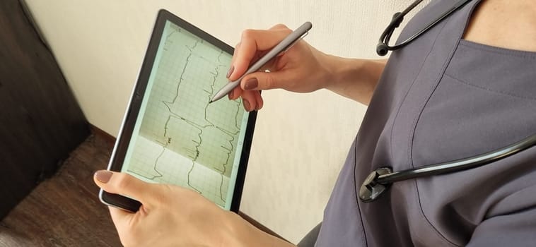 Shot of the female doctor in uniform against the white wall studying cardiogram on the tablet