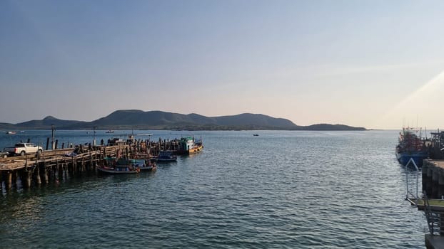 Samaesarn, Sattahip Thailand 17 March 2024 vast body of water glimmers under the sun next to a weathered pier, where seagulls soar and the gentle waves lap against the wooden posts.