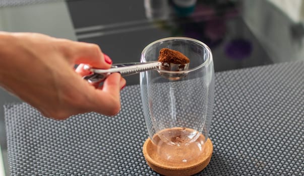 Shot of the ground coffee being added to transparent cup to brew a coffee.