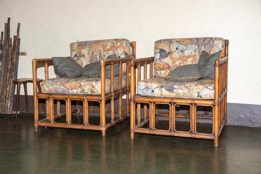 two bamboo chairs in a lodge in South Africa with cushions and images of wild animals