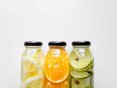 Lemon, orange, and lime detox drinks in glass bottles on white background with copy space. Concept for design and print. High quality photo