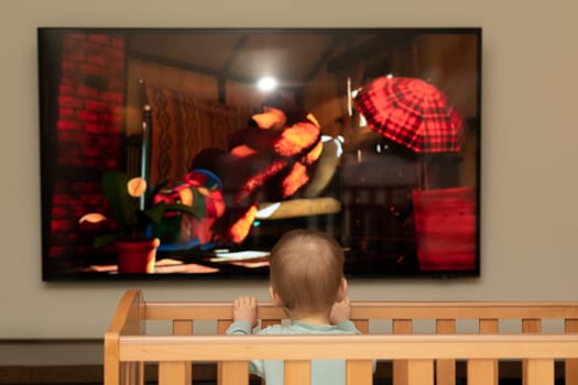 Bright cartoons fascinate a small child when he looks at the screen.