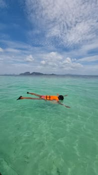 A woman peacefully floats in the ocean on a surfboard, embracing the tranquility of the water beneath her. Koh Kradan Thailand