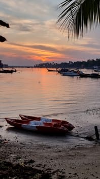 A vibrant red and white boat rests peacefully on the sandy beach, its colors contrasting against the blue sea and golden shoreline. Koh Libong Thailand