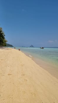 A serene sandy beach where a lone boat gently floats in the calm waters, surrounded by the beauty of nature. Koh Kradan Thailand