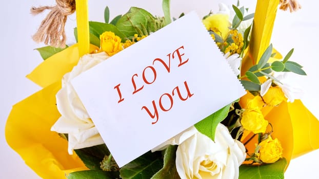 words I love you on a white leaf on a bouquet of bright beautiful flowers