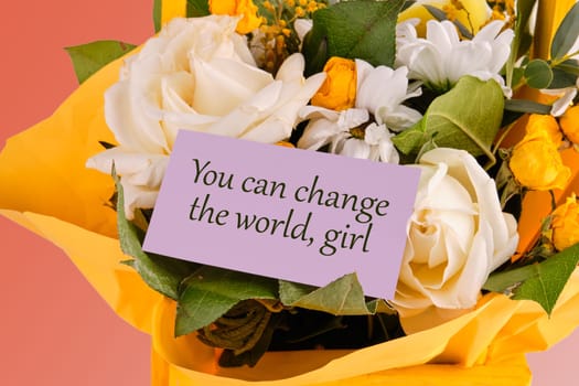 You can change the world, girl text written on a purple business card in a bouquet of flowers