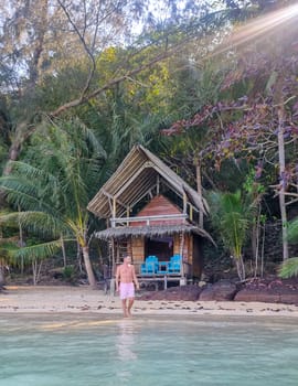 A man standing peacefully on a sunny beach in front of a traditional hut, soaking in the beauty and serenity of the surroundings. Koh Wai Thailand