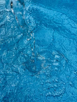 Background dynamic splash of clear water creating swirling wave in blue water with droplets suspended in motion. Clean water concept. High quality photo