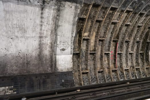 London, United Kingdom - February 02, 2019: Old dirty wall in tube train tunnel, missing London Underground logo on concrete