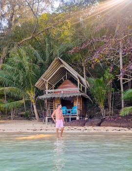 A man standing in the serene waters in front of a rustic hut, surrounded by nature and tranquility. Koh Wai Thailand