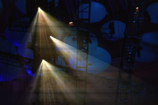 Reflector lights shining through smoke on theatre roof before performance