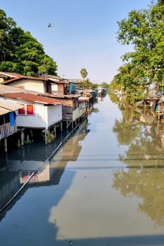 Bangkok Thailand 13 January 2024, , A tranquil body of water dotted with charming houses, reflecting the sky and surrounding greenery on its glassy surface.