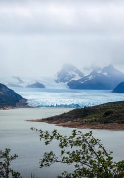 Glacier meets lake amidst mountains.
