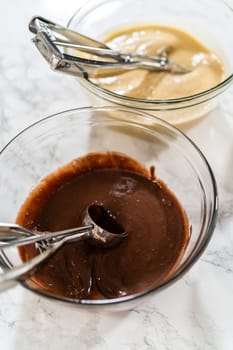 Cupcake foil liners are being meticulously filled with both chocolate and vanilla batter, setting the stage for the baking of deliciously diverse birthday cupcakes.