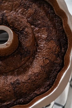 With precision, the Chocolate Bundt Cake is carefully removed from the pan - placed onto a round cooling rack, preparing it for a flawless presentation and delightful indulgence.