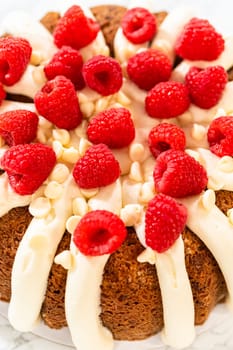 With precision, the White Chocolate Raspberry Bundt Cake is carefully removed from the pan - adorned with luscious cream cheese frosting, creating a delectable treat that is sure to delight.
