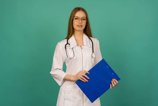 Beautiful young girl nurse or trainee doctor with blue folder and statoscope on a blue background - image
