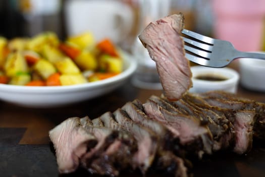 Close-up of female hand holds Pieces of roasted meat. Woman hand holding with grilled beef steak. Concept of eating out.