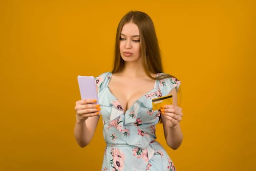 Lady buying online with a credit card and smart phone on yellow background - image