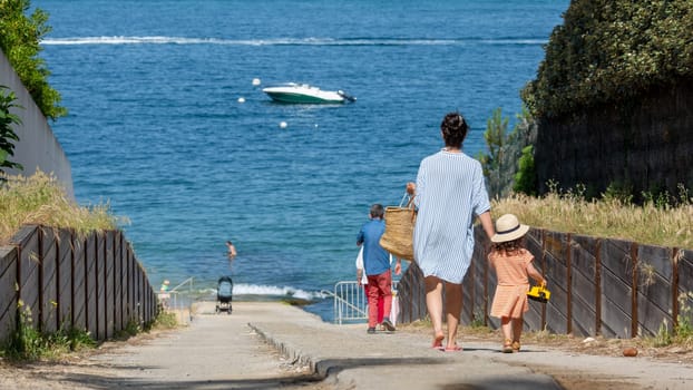 young woman and her little daughter going to the sea