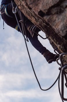 Man in body harnesses feature life-safety, attaches hooks to iron brackets, climbs rock, active lifestyle of people, mountaineering, viaferrata in mountains of pyrenees, High quality photo