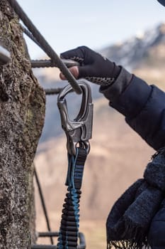 Climbing rope slides in a carabiner and mountain stream in the background, Insurance climbers closeup. High quality photo