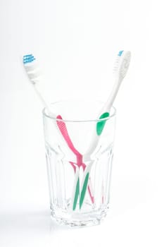 Toothbrushes in glass on table on light background